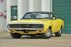 a yellow muscle car parked in front of a building