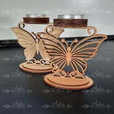 two wooden candlesticks with butterflies on them sitting next to each other in front of a mirror