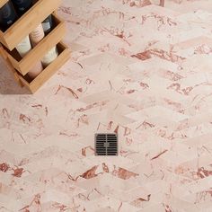 a bathroom with pink marble flooring and shelving unit on the wall next to it