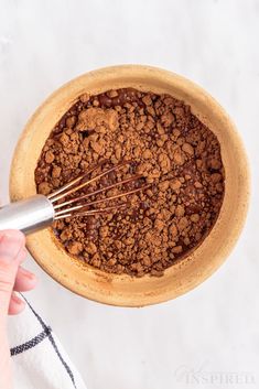 a person whisking chocolate in a wooden bowl with a metal beater on top