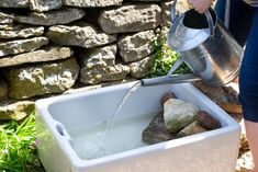 a person pouring water into a bucket filled with rocks