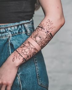 a woman's arm with flowers on it and a ring around the wrist tattoo