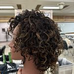 the back of a woman's head with curly hair in a barbershop