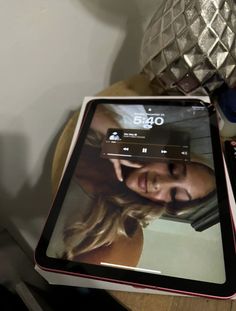 a tablet computer sitting on top of a wooden table next to a vase with flowers