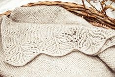 a knitted blanket sitting on top of a basket next to some branches and twigs