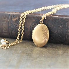 "A lovely gold filled locket graces this necklace. The vintage piece has a lovely floral design etched on the front; the back is plain. The gold filled pendant is hallmarked on the inside which has two frames to place your beloved photos. The locket has been set on a new 14k gold filled chain accented with tiny white pearls at the clasp. Locket 25x15mm Necklace 18\" (45cm) ✦All of our vintage lockets ship with complimentary insurance✦ ✤Our entire selection of lockets can be found here✤ http://ww Gold Locket Necklace With Intricate Design, Silver Locket Necklace Vintage, Gold Locket Necklace With Intricate Design And Round Pendant, Gold Brass Locket Necklace For Anniversary, Heirloom Gold Pendant Locket Necklace, Gold Locket Necklace With Intricate Round Pendant, Oval Locket Necklace With Intricate Design For Anniversary, Victorian Gold Jewelry For Wedding, Victorian Gold Wedding Jewelry