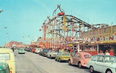 an old photo of cars parked in front of a roller coaster at the amusement park