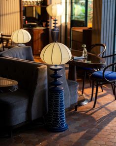 two lamps sitting on top of a table next to couches and tables in a room