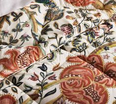 the comforter is made up with colorful flowers and leaves on it's side