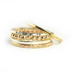 "Stylish Mixed Hammered Stackable Rings Set of 5. Sterling silver and 14k gold-fill metal is forged and hammered to create this textural look. Layer all these beautiful Aquarian Thoughts rings together or wear them one by one. Listing includes a mixture of 2 \"Tree Bark\" Stacking Rings (1 GOLD & 1 SILVER), 2 \"Finely\" Hammered Stacking Rings (1 GOLD & 1 SILVER) and 1 GOLD Beaded Stacking Ring. Select ring size from drop down menu or contact us for custom requests. Ring bands measures a Gold Hammered Stackable Rings For Anniversary, Adjustable Gold Hammered Stackable Rings, Hammered Yellow Gold Stackable Rings In Sterling Silver, Hammered Toe Ring Jewelry For Anniversary, Hammered Gold Mixed Metal Jewelry, Hammered Mixed Metal Gold Jewelry, Handmade Gold Stackable Rings In Sterling Silver, Beaded Stacking Rings, Gemstone Stacking Ring