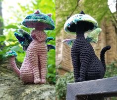 two crocheted cats sitting on top of a wooden bench next to each other