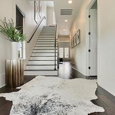 a large white cowhide rug on the floor in front of an entry way with stairs