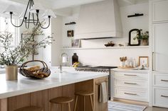 a kitchen with white cabinets and counter tops, an island in front of the stove