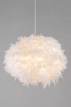 a white light hanging from a ceiling fixture with feathers on the top and bottom of it