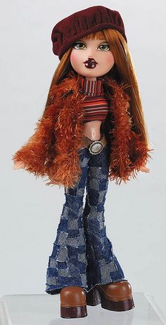 a doll with long red hair wearing jeans and a hat on top of a white surface