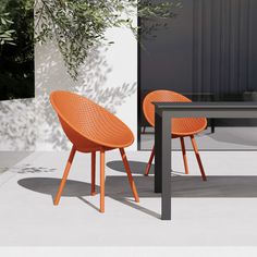 two orange chairs sitting next to each other near a table