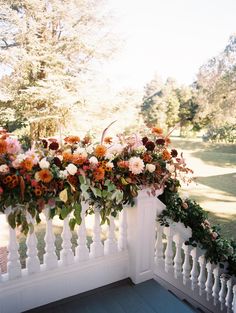 an arrangement of flowers on a white fence