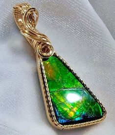 This is a very beautiful multicolored Ammolite gemstone with bright color tones of green, yellow, orange, and a touch of blue.  I have hand framed this gorgeous fossil gemstone in solid 14K Gold Filled wire. The pendant measures approximately 2 inches from the top of the bail to the bottom of the pendant.  It is 3/4 inch in width.  The bail is generously sized in order to accommodate a variety of chain widths.  A handcrafted pendant and unique and rare stone,  it is one of a kind. A gift box is included. This beautiful and unique genuine Canadian Ammolite gemstone was found  in the Bear Paw region in southern Alberta Canada.  Ammolite is an ancient fossil and is the world's oldest and most rare gem. Ammolite with the most beautiful color is found only in southern Alberta.  This stone was p Multicolor Oval Jewelry With Natural Inclusions, Green High Luster Jewelry For Gift, High Luster Green Jewelry For Gift, Southern Alberta, Pale Aqua, Bear Paw, Rare Stone, Peacock Green, Rare Gems