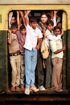 a group of young men standing on the side of a train with their hands in the air