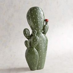 a ceramic cactus with a red flower in it's mouth sitting on a white surface