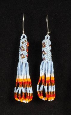 two pairs of beaded earrings with orange and white beads on black background, close up