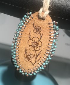 a wooden ornament with beads and flowers on it