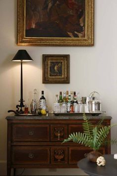 a painting hanging on the wall above a bar with liquor bottles and glasses sitting on top of it