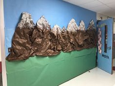 a bulletin board with mountains on it in an office cubicle decorated to look like they're climbing the mountain