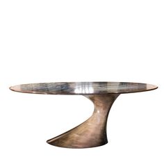 an oval metal table sitting on top of a white wall