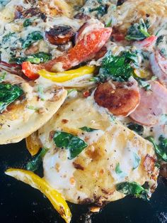 a pizza topped with lots of toppings on top of a black plate next to other food items