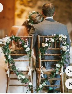 two people sitting on chairs with flowers and greenery in their lapels, facing each other