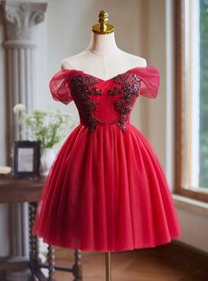 Feminine grace and stunning embellishments make this dress unforgettable! This red homecoming dress is all about making a bold, glamorous statement. The off-the-shoulder sleeves are made of delicate tulle, providing a soft and romantic touch to the overall design. The bodice, adorned with intricate black beadwork and sequins, adds a layer of elegance and sophistication. The embellishments create a beautiful floral pattern that sparkles under the lights, drawing attention to the detailed craftsmanship. The fitted bodice transitions into a full tulle skirt, allowing for fluid movement and adding volume to the silhouette. The rich red hue of the dress is striking on its own, but the black detailing truly elevates the look to something extraordinary. Whether you're attending homecoming or a fo Off Shoulder V Neck, Dress With Beads, Winter Wedding Venues, Grey Prom Dress, Tulle Homecoming Dress, Burgundy Shorts, Red Homecoming Dresses, Tulle Sleeves, Elegant Prom Dresses