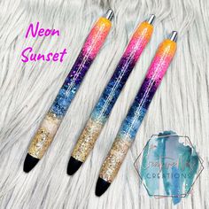 three pens with different designs on them sitting on top of a white fur covered surface