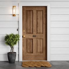 a wooden door on the side of a white house next to a potted plant