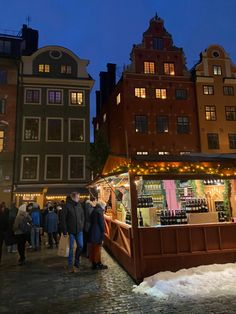 people are standing in front of a small christmas market