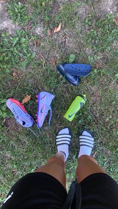 a person standing in the grass with their feet up next to several pairs of shoes