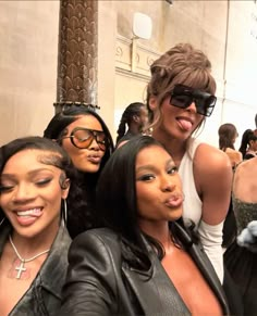 three women taking a selfie in front of a crowd at an event with one woman sticking out her tongue