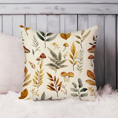 a white pillow with leaves and mushrooms on it sitting on a furnishing area