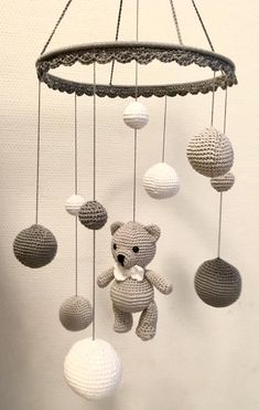 a crocheted teddy bear is hanging from a chandelier made of balls