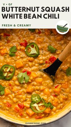 a pot filled with beans and vegetables next to a wooden spoon