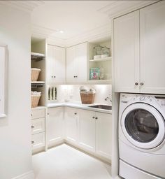 a washer and dryer in a white laundry room with cabinets on either side