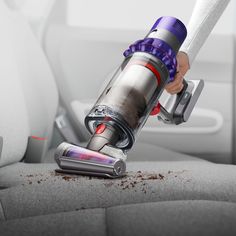 a person using a vacuum cleaner on the seat of a car