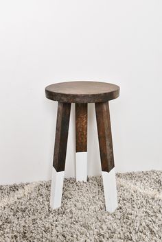 a small wooden table sitting on top of a carpeted floor next to a white wall