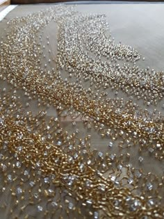 gold and silver sequins are scattered on a sheet of fabric in front of a window