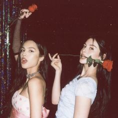 two women standing next to each other with roses in their mouths and one holding a rose