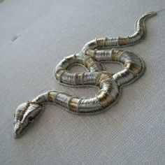 the snake is made out of silver wire and sits on top of a white cloth