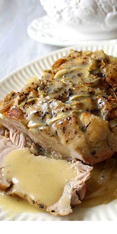 a white plate topped with meat covered in gravy and sauce on top of a table