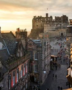 people are walking around in the city at sunset or dawn, with castle like buildings on either side