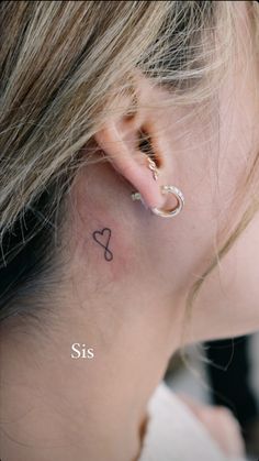 a woman's ear has a small tattoo on it