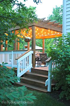 a gazebo with string lights on it in front of a deck and patio area